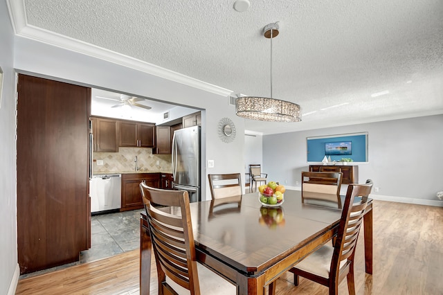 dining room with ornamental molding, light hardwood / wood-style flooring, and a textured ceiling