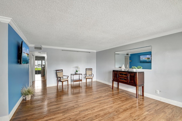 sitting room with ornamental molding, light hardwood / wood-style floors, and a textured ceiling