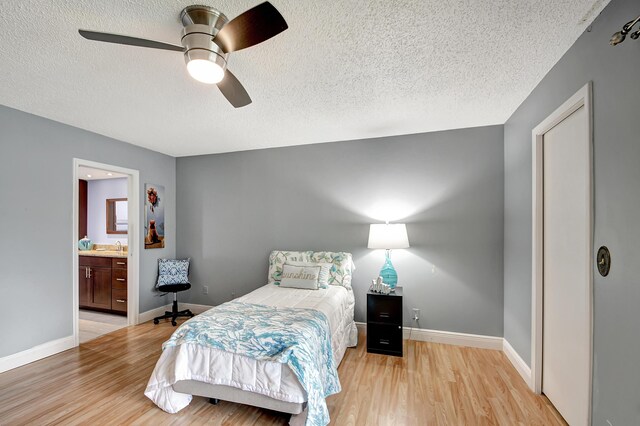 bedroom with ceiling fan, light hardwood / wood-style floors, a textured ceiling, and ensuite bathroom