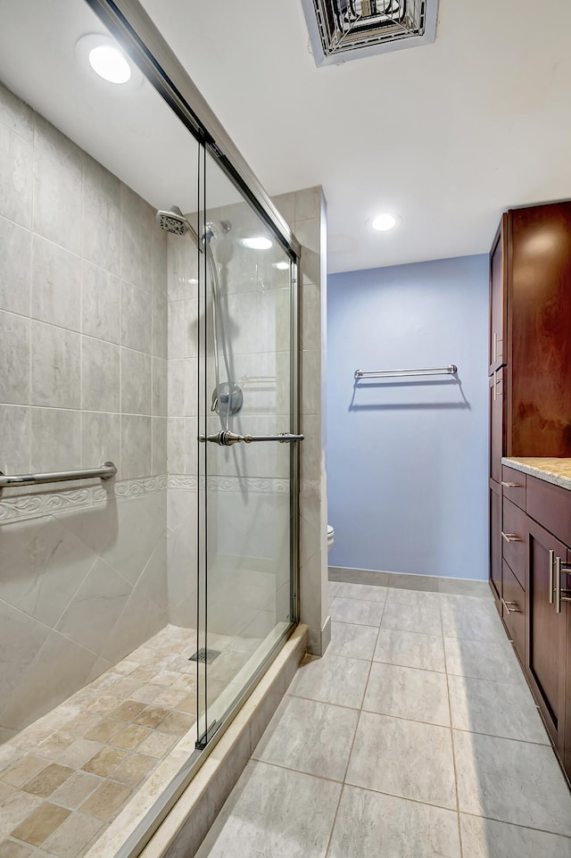 bathroom with tile flooring, vanity, toilet, and a shower with door