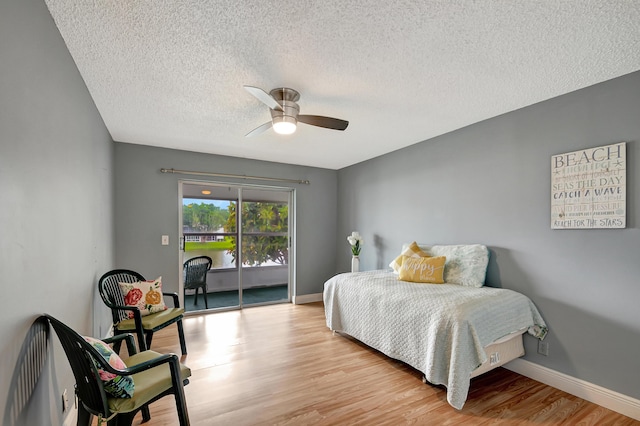 bedroom with ceiling fan, access to outside, a textured ceiling, and light hardwood / wood-style floors