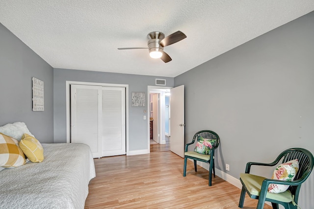 bedroom featuring a closet, ceiling fan, light hardwood / wood-style floors, and a textured ceiling