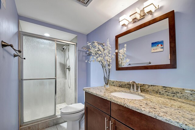 bathroom featuring tile flooring, walk in shower, vanity, and toilet