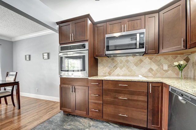 kitchen with appliances with stainless steel finishes, backsplash, crown molding, light stone countertops, and a textured ceiling