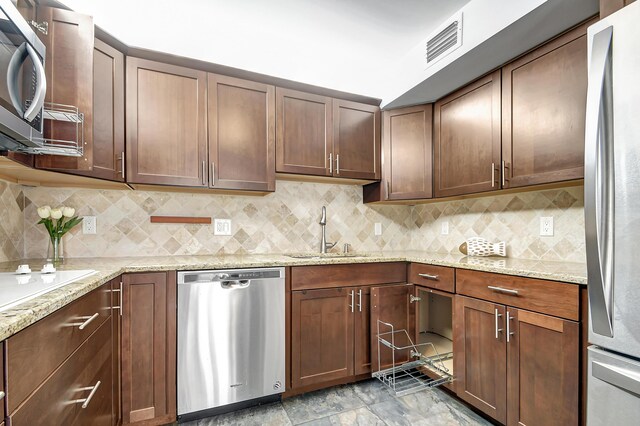 kitchen featuring sink, backsplash, light tile floors, and stainless steel appliances