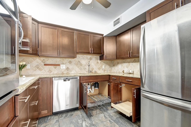 kitchen featuring light stone countertops, ceiling fan, backsplash, tile floors, and appliances with stainless steel finishes