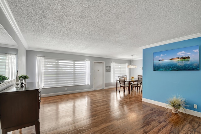 living room with hardwood / wood-style flooring, ornamental molding, an inviting chandelier, and a textured ceiling