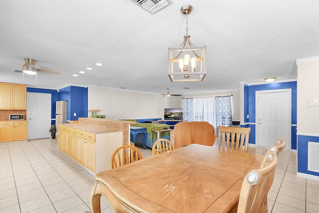 tiled dining area with ceiling fan with notable chandelier, ornamental molding, and a textured ceiling