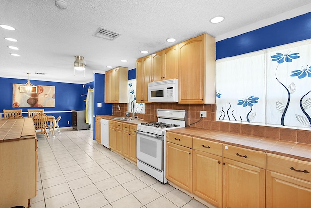 kitchen featuring tile counters, sink, backsplash, decorative light fixtures, and white appliances