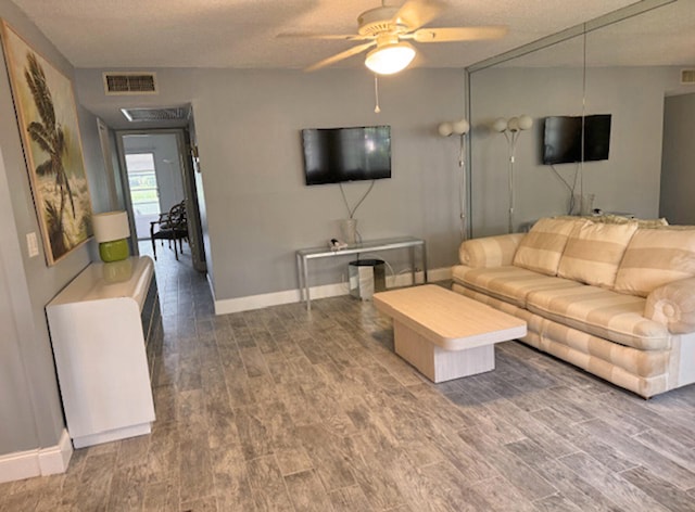 living room featuring hardwood / wood-style floors, ceiling fan, and a textured ceiling