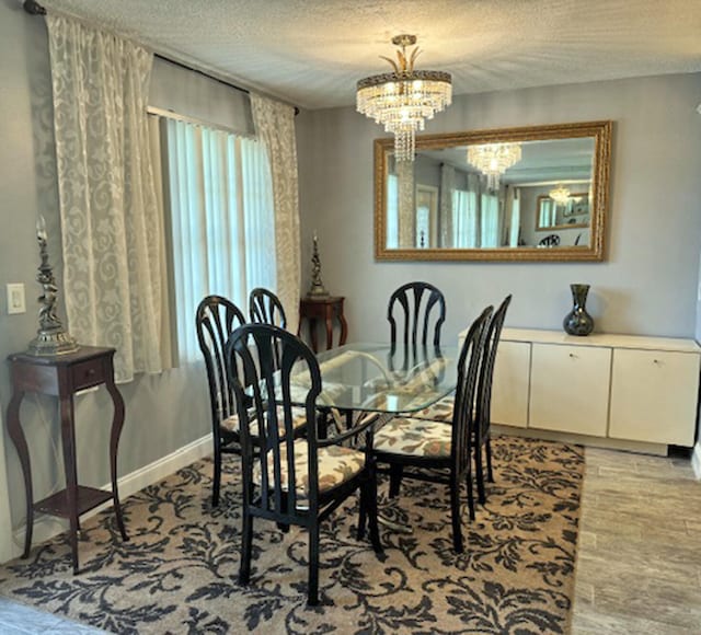 dining room featuring light hardwood / wood-style flooring, a notable chandelier, and a textured ceiling