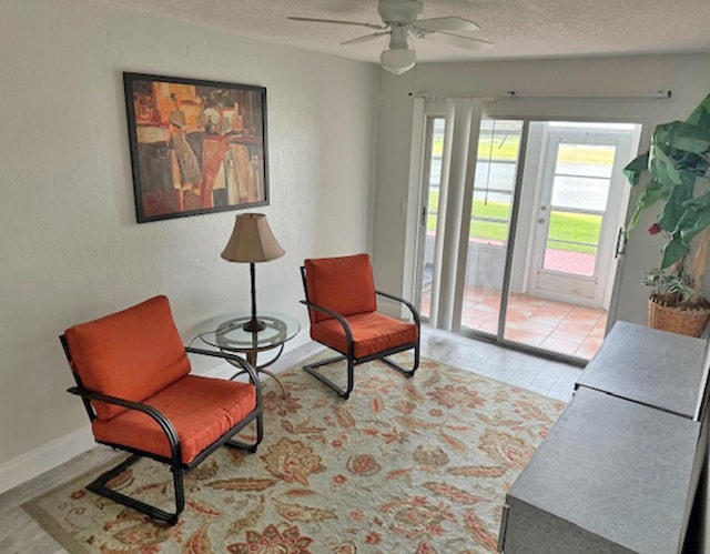 sitting room featuring a textured ceiling, light hardwood / wood-style flooring, and ceiling fan