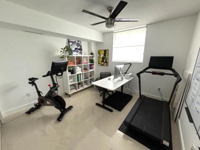 exercise room with ceiling fan and light tile patterned flooring