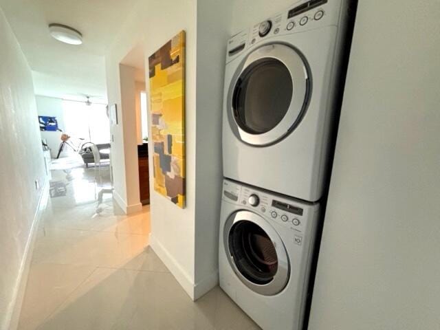 clothes washing area featuring light tile patterned floors and stacked washer and clothes dryer