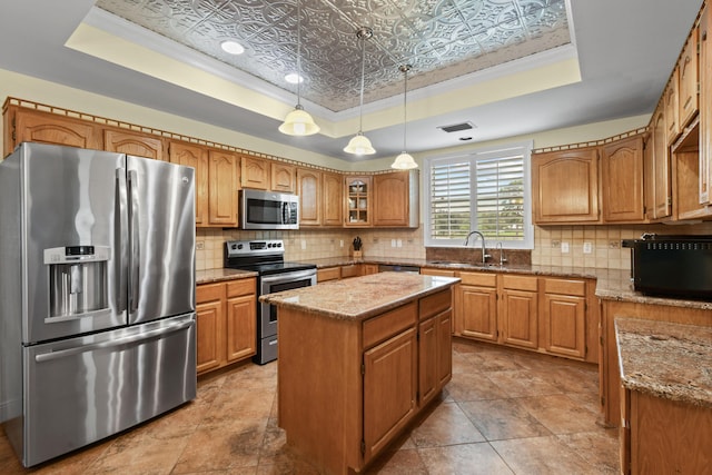 kitchen with an ornate ceiling, appliances with stainless steel finishes, decorative backsplash, and a tray ceiling