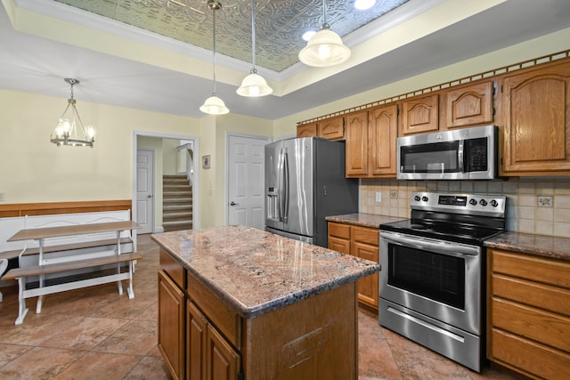 kitchen featuring appliances with stainless steel finishes, a tray ceiling, an ornate ceiling, and backsplash