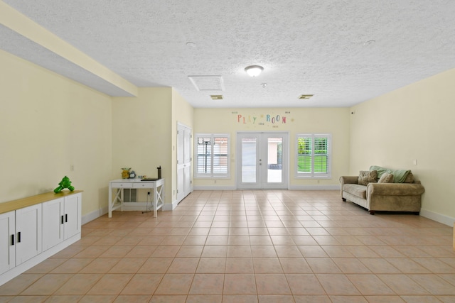 interior space featuring light tile patterned floors, baseboards, a textured ceiling, and french doors