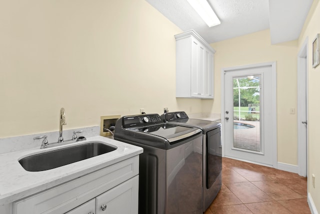 laundry room with a textured ceiling, separate washer and dryer, a sink, cabinet space, and tile patterned floors