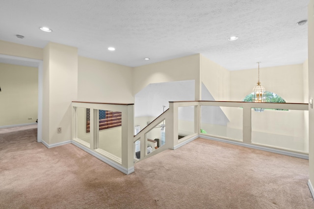 hall with recessed lighting, carpet flooring, a textured ceiling, and an upstairs landing