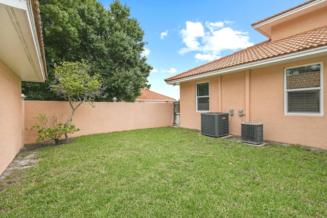 view of yard featuring fence and central AC