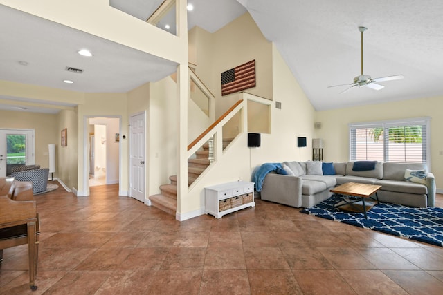 living area featuring ceiling fan, high vaulted ceiling, visible vents, baseboards, and stairs