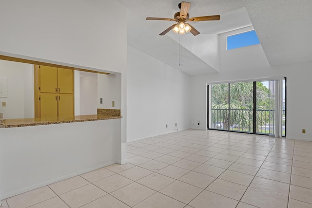 unfurnished living room featuring a towering ceiling, ceiling fan, and light tile patterned flooring