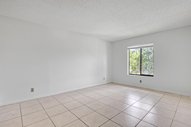 spare room featuring light tile patterned floors and a textured ceiling