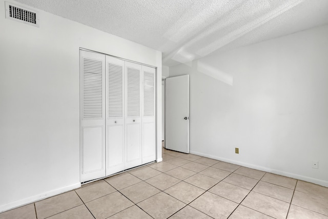 unfurnished bedroom featuring a closet, light tile patterned floors, and a textured ceiling