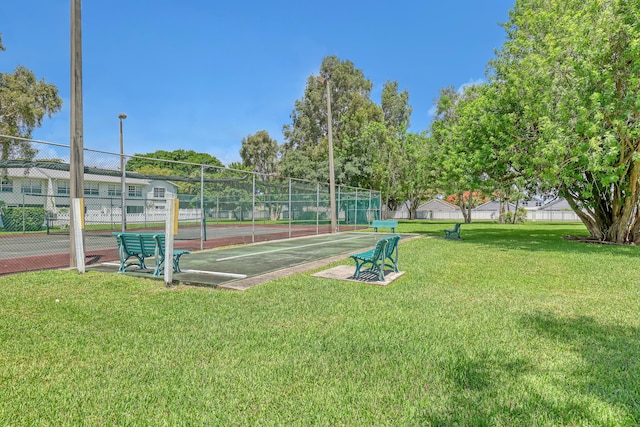 view of property's community featuring tennis court and a lawn