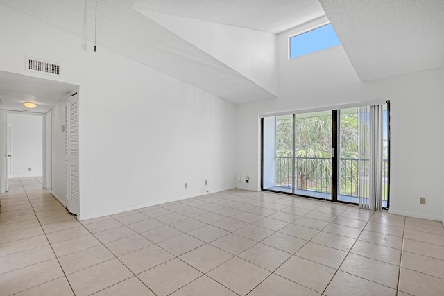 unfurnished room featuring a healthy amount of sunlight, light tile patterned floors, and a towering ceiling