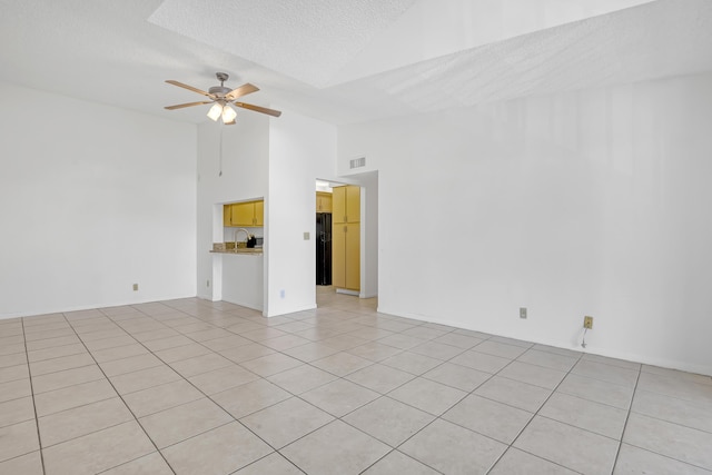 tiled empty room with ceiling fan, sink, a textured ceiling, and high vaulted ceiling