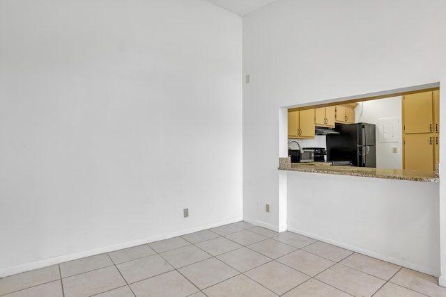 kitchen with stone counters, black refrigerator, and light tile patterned floors