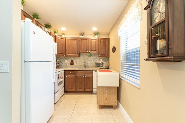 kitchen with backsplash, light tile patterned flooring, white appliances, and sink