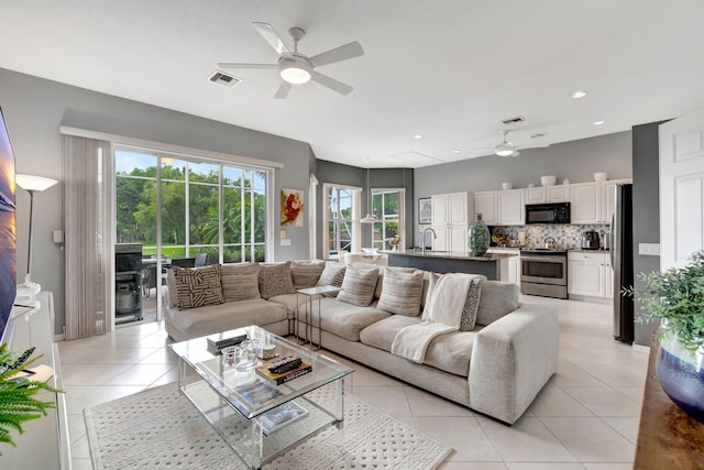 living room featuring ceiling fan, light tile patterned flooring, and sink