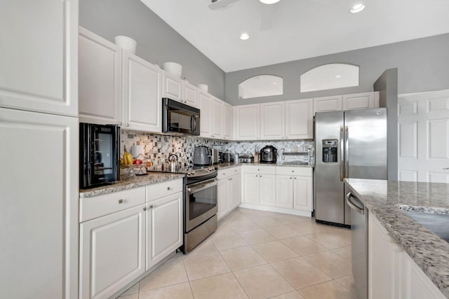 kitchen with appliances with stainless steel finishes, backsplash, light stone counters, white cabinetry, and light tile patterned flooring