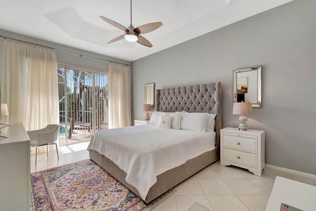 tiled bedroom with ceiling fan, access to exterior, and a tray ceiling