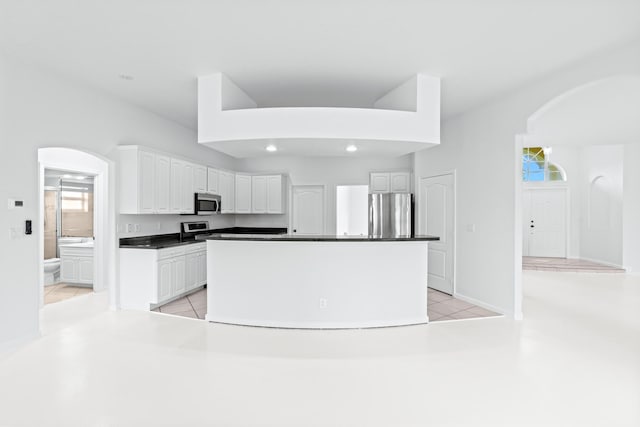 kitchen with appliances with stainless steel finishes, a center island, white cabinetry, and light tile patterned floors