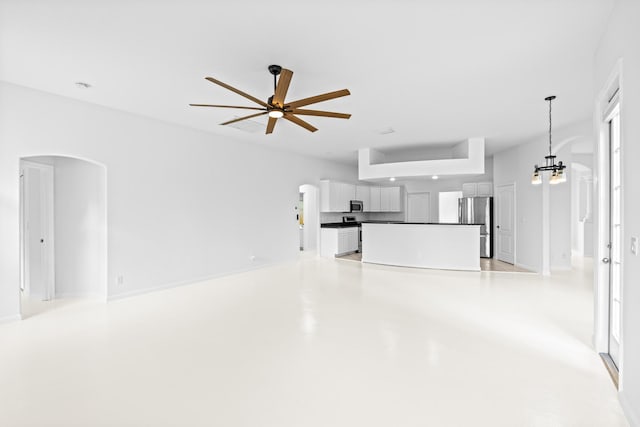 unfurnished living room with ceiling fan with notable chandelier