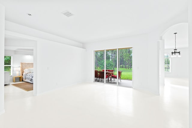 spare room with concrete floors and an inviting chandelier