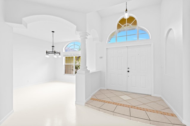 foyer entrance with a chandelier, tile patterned floors, and ornate columns