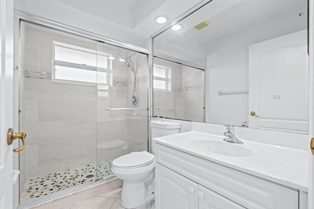 bathroom featuring tile patterned flooring, vanity, a shower with shower door, and toilet