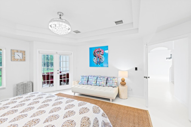 bedroom with a chandelier, french doors, carpet floors, and a raised ceiling