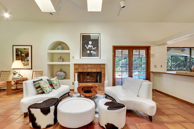 tiled living room with a tile fireplace, french doors, and a skylight