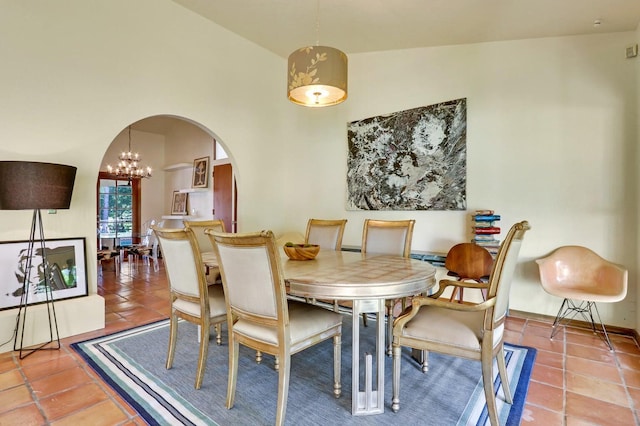 dining space featuring tile patterned floors, lofted ceiling, and a notable chandelier