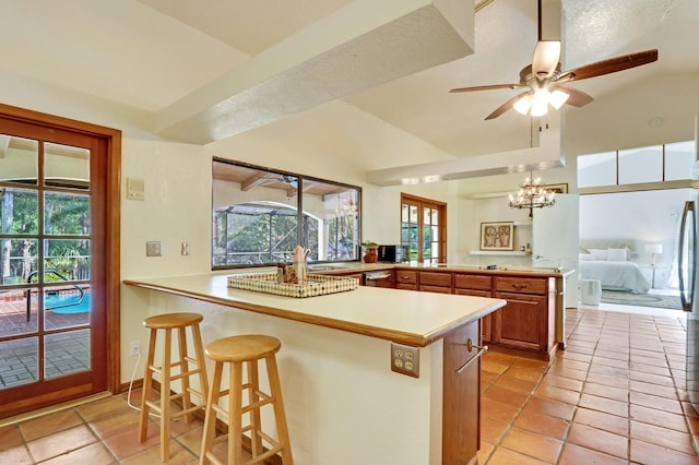 kitchen with kitchen peninsula, a kitchen breakfast bar, lofted ceiling, and light tile patterned flooring