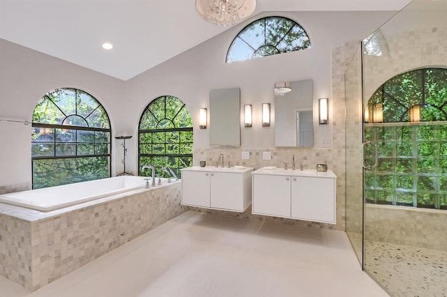 bathroom featuring vanity, independent shower and bath, and lofted ceiling