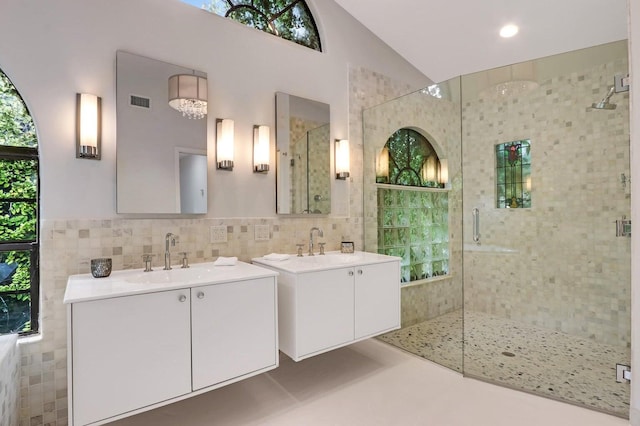 bathroom featuring vaulted ceiling, vanity, tile walls, and walk in shower