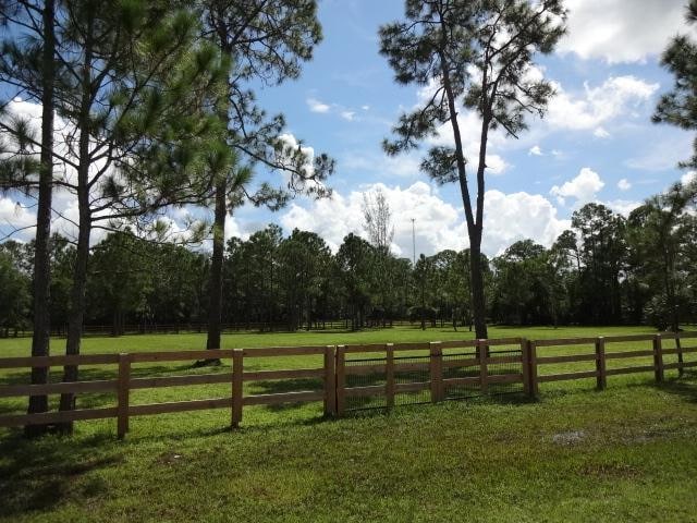 view of gate with a lawn and a rural view