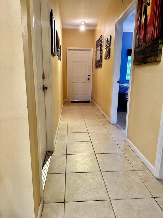 hall with light tile patterned floors and a textured ceiling