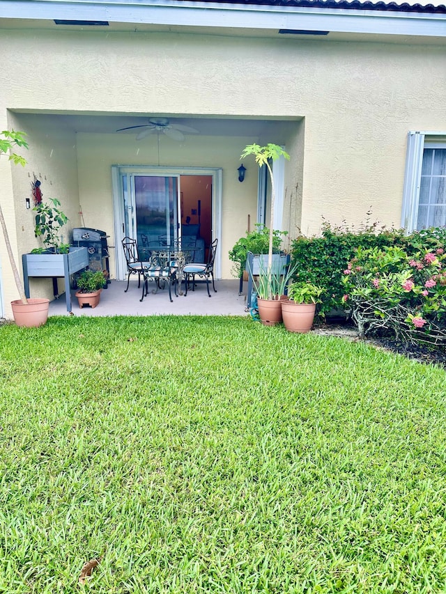 entrance to property featuring ceiling fan, a yard, and a patio area